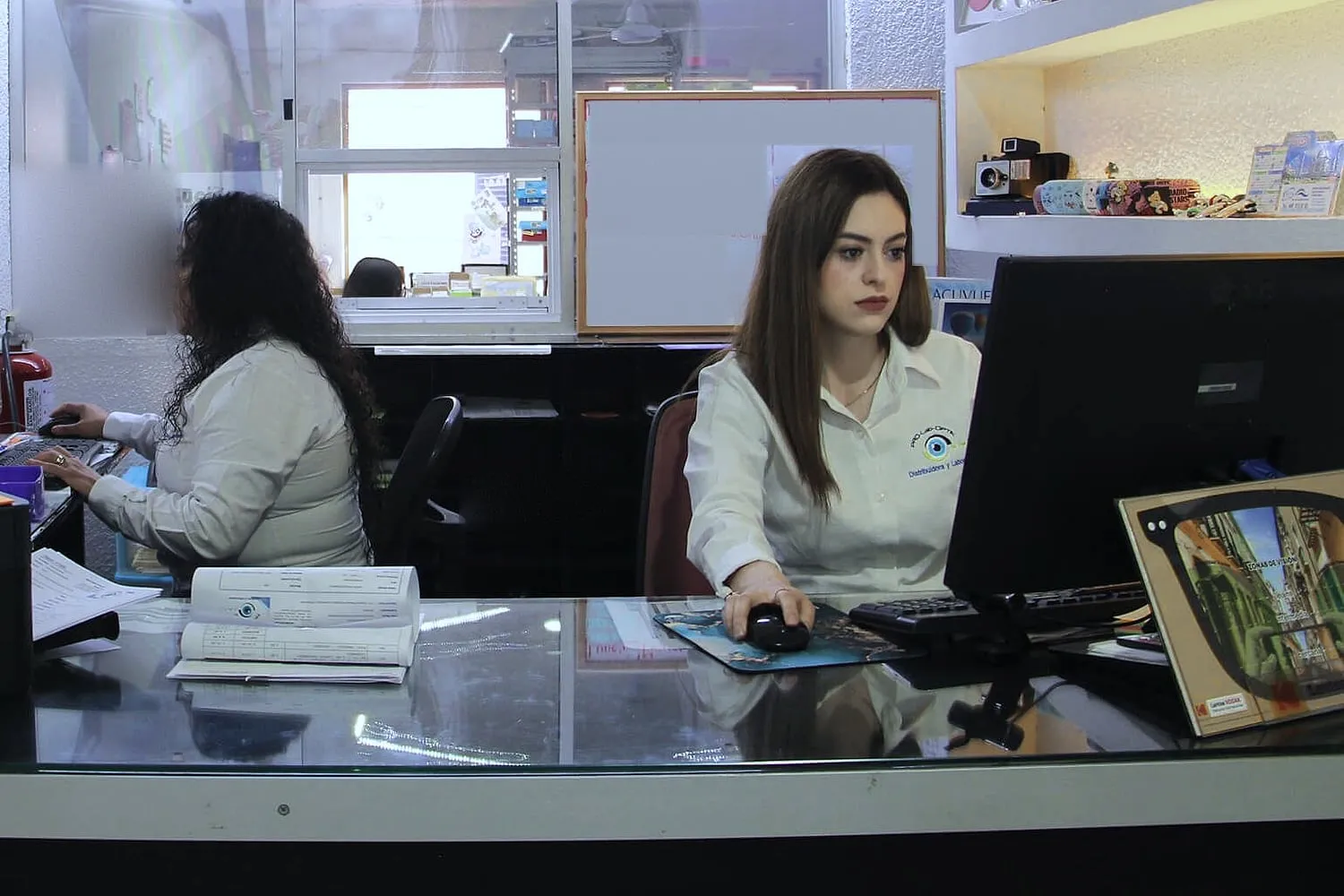 Dos colaboradoras trabajando con sus computadoras en el mostrador de recepción del laboratorio